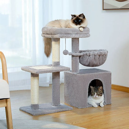 chat couché sur le couchage supérieur et chat tigré et blanc dans la niche d’un petit arbre à chat gris. 